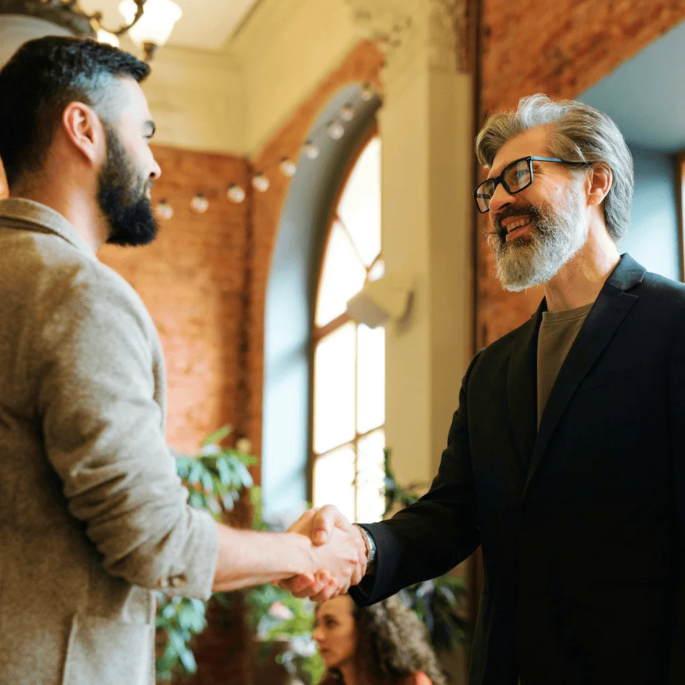 Two businessmen shaking hands in a brick-walled office