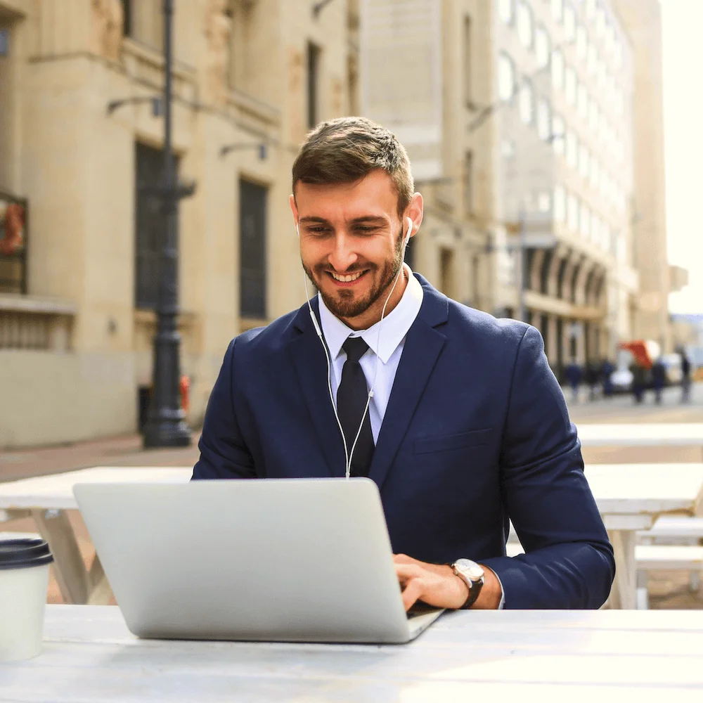 Founder smiling while working on a laptop outdoors in the city
