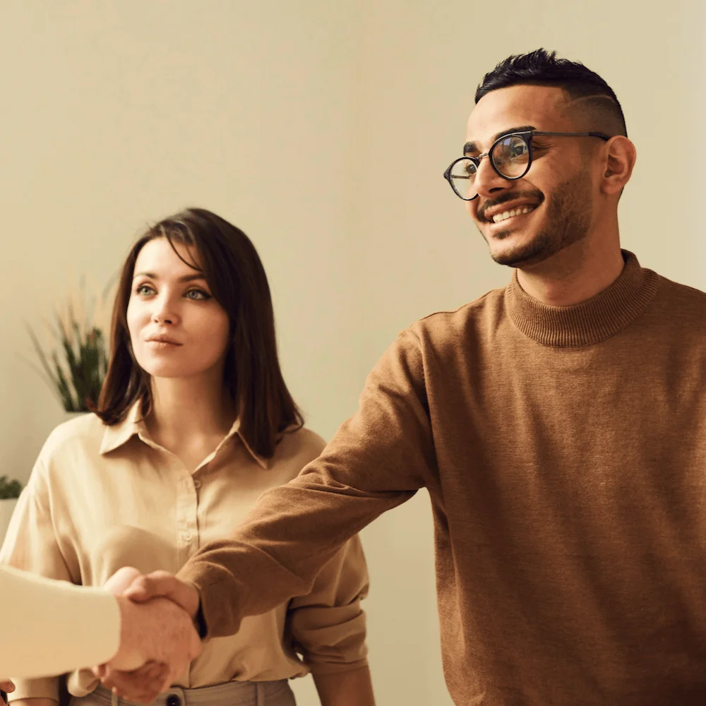 Two professionals smiling as they shake hands