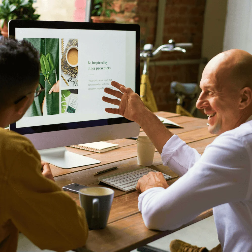 Two colleagues reviewing a website design on a desktop monitor